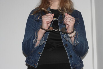 A blonde woman stands with her hands handcuffed in front of her after being arrested