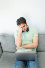 Fototapeta premium A young freelancer has a sore neck due to excessive work on his laptop at home. Concept of distance work and online learning
