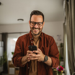 Portrait of adult man stand and hold mobile phone text message at home