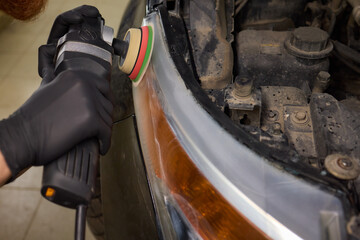 Fototapeta premium Person using a machine to polish automotive lighting on a car headlight