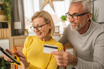 Mature caucasian husband and wife shopping online sit at home