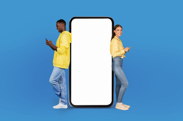 Multiracial lovers stand back-to-back, each engaged with their own smartphone. They seem oblivious to the large, blank smartphone screen mockup that visually divides them