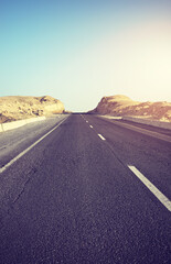 Desert road at sunset, front focus on asphalt, color toning applied, Egypt.