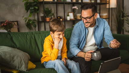 Father and son watch movie or cartoon on tablet at home