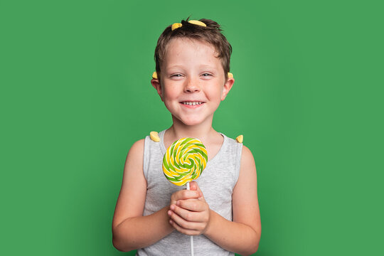 Smiling boy with lollipop on green background