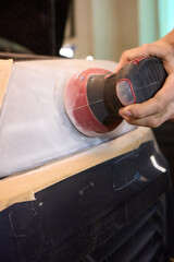 Person using a machine to polish automotive lighting on a car headlight