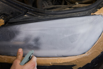 Person using a machine to polish automotive lighting on a car headlight