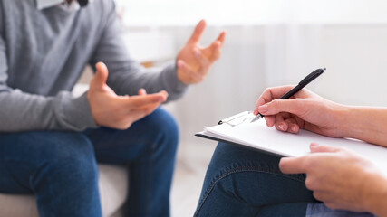A person is seated in a neutral-colored office space, engaging in a discussion with another...