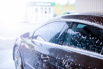 Applying foam for washing the car in bright sunlight