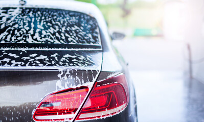 Rear view of a car with white foam applied at the car wash