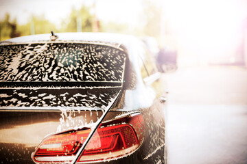 Rear view of a car with white foam applied at the car wash