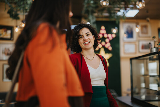 Two friends enjoy a casual conversation with warm smiles in the inviting atmosphere of a local cafe.