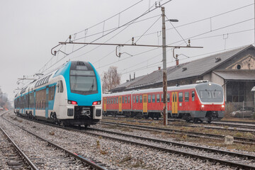 Old and new passenger trains on adjacent train tracks. Old making way for new in rail...