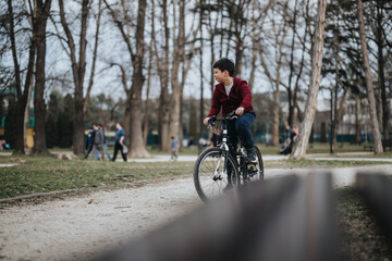 Obraz premium A young boy riding his bike in an urban park, surrounded by lush greenery and enjoying nature.