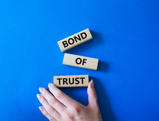 Bond of trust symbol. Wooden blocks with words Bond of trust. Beautiful blue background. Businessman hand. Business and Bond of trust concept. Copy space.