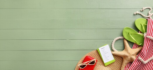 Notebook with check-list of things to pack for travel on green wooden background with space for text