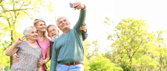 Group of happy senior people taking selfie in park