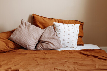 A bed with two pillows, one of which has a star pattern. The bed is covered in a brown comforter