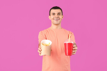 Young man with french fries and cola on purple background
