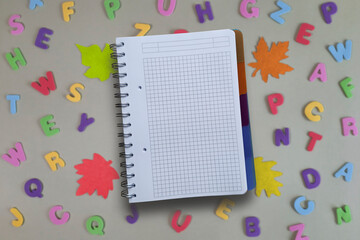 Empty page. School notebook on background of alphabet letters and autumn leaves. Back to school or...