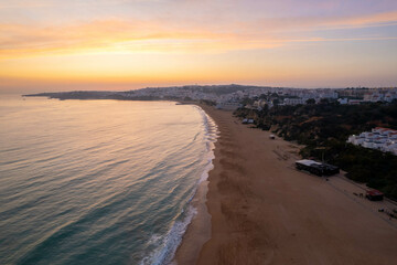 Aerial Drone View of the Blue Ocean and Waves Crashing Along the Beach in Albufeira Portugal at Sunset