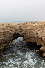 Views of Waves Crashing in on an Enclave Created by the Cliffside on a Hazy Day in Albufeira...