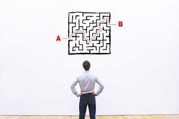solution concept, find exit from the maze, businessman looking at labyrinth drawing
