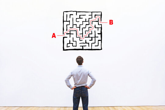 solution concept, find exit from the maze, businessman looking at labyrinth drawing