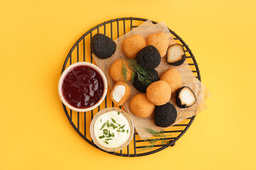 Stand with different delicious fried mozzarella balls and sauces on orange background