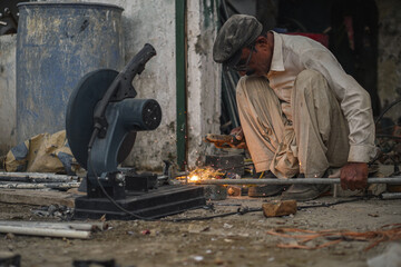 Welder welding pipes in his Workshop