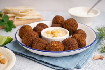 Plate with delicious falafel balls and hummus on light background