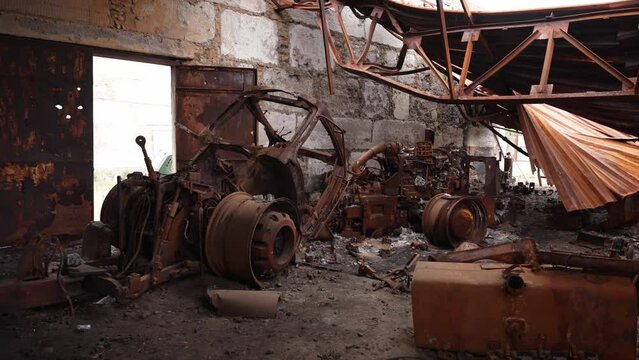 Crushed agricultural machinery inside destroyed warehouse. Concept of war, destruction, oblivion