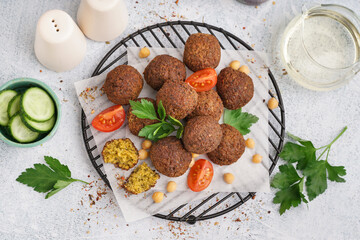 Stand with delicious falafel balls, chickpea and tomato on light background