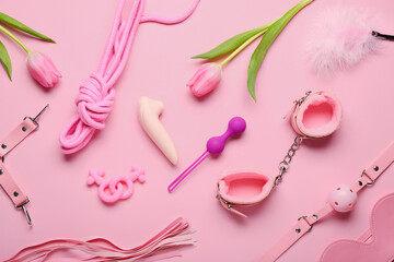 Composition with different sex toys and tulip flowers on pink background