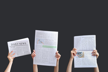 Female hands with newspapers on black background