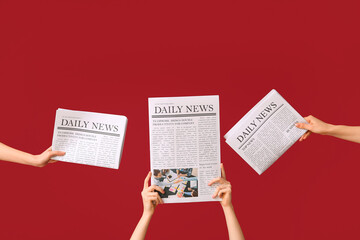 Female hands with newspapers on red background