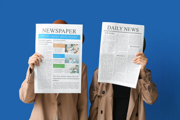 Women in cloak and hat with newspapers on blue background
