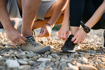 Close up view of hands of athletic man in white t-shirt and woman in black top tying shoelaces...