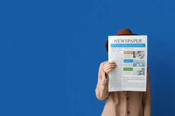 Woman in cloak and hat with newspaper on blue background