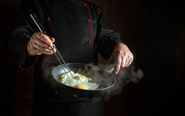 The chef is preparing scrambled eggs in a frying pan for breakfast. The concept of preparing...