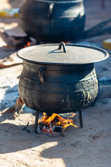 three legged african black cast iron pot cauldron, cooking outdoors, slow cooking