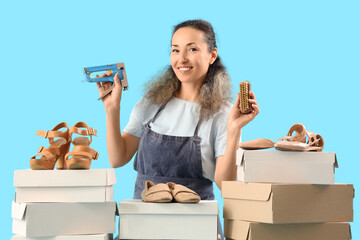 Female shoemaker with staple gun, brush and boxes on blue background