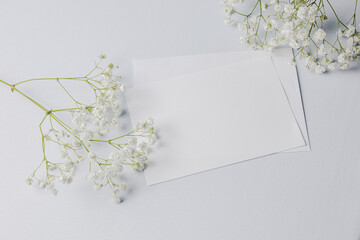 Invitation or greeting card mockup with envelope and flowers on white background, mockup