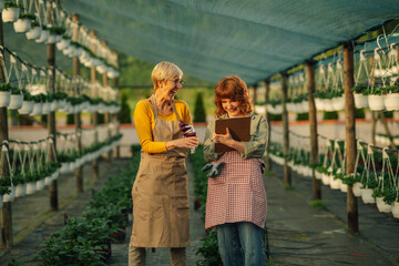 Female horticulturalists laughing together in open greenhouse garden