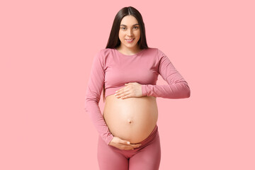 Sporty pregnant woman against pink background