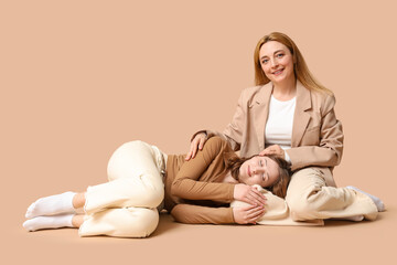 Beautiful young woman lying on her mature mother's knees brown background. Mother's Day celebration