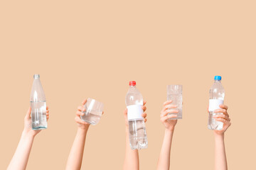 Female hands with bottles and glasses of water on color background