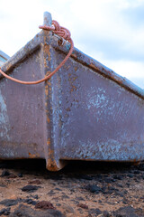 A boat is sitting on the ground with a rope tied to it. The boat is old and rusty, and it is...