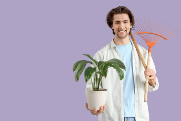 Handsome man with plant and rakes on lilac background