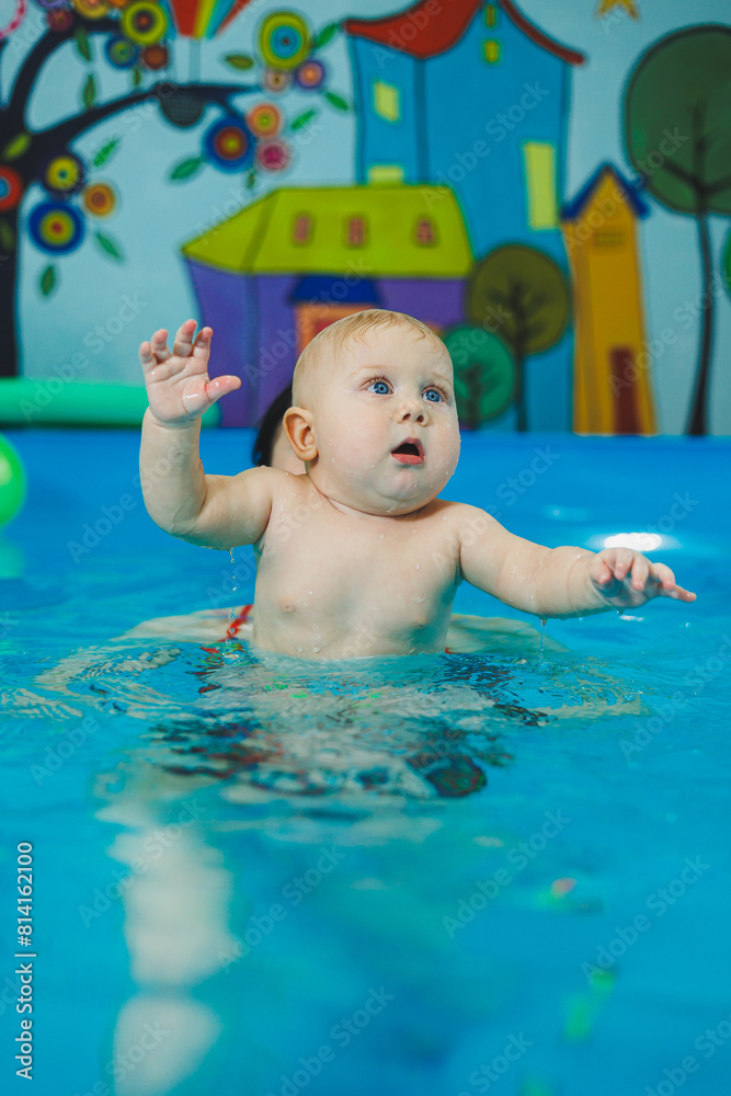 Wall mural swimming pool for babies. a baby learns to swim with a coach